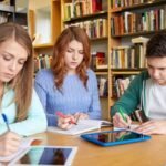 estudiantes-felices-con-libros-y-computadoras