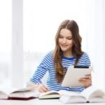 estudiantes-sonrientes-con-libros-y-computadoras