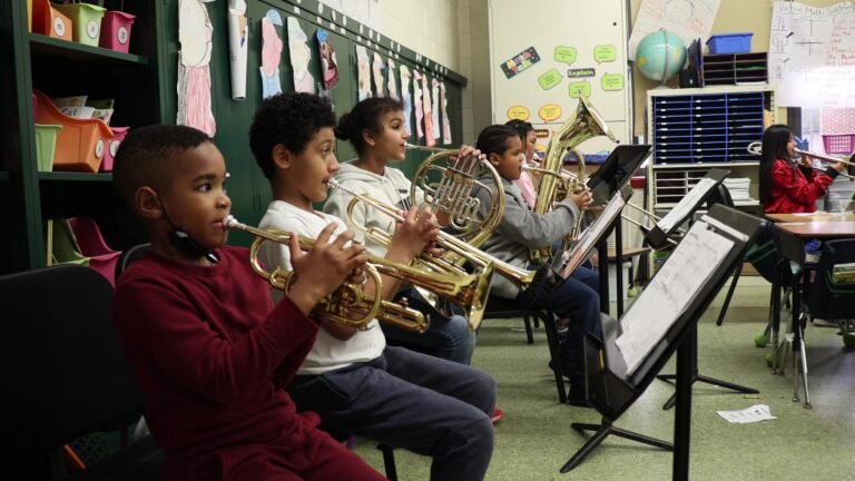 Por qué Elegir La Escuela De Música De Coronel Suárez Para Aprender 27 estudiantes tocando instrumentos en aula musical