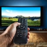 Cómo Ingresar El Código de Prime Video en Mi Televisor mano-usando-control-remoto-frente-a-televisor