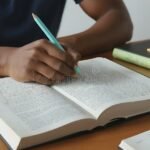 Cómo Hacer Marcos Teóricos Efectivos Para Trabajos Académicos persona-escribiendo-en-cuaderno-con-libros-abiertos