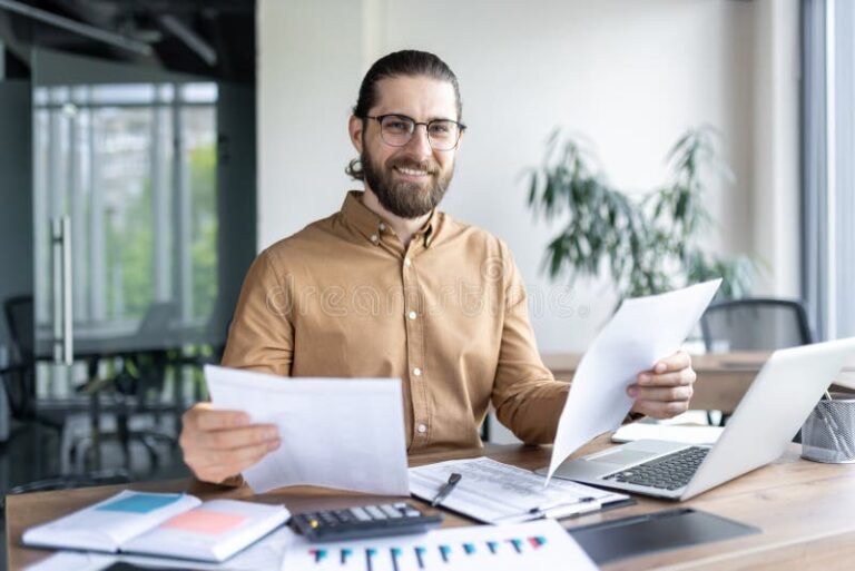 persona revisando documentos y computadora abierta